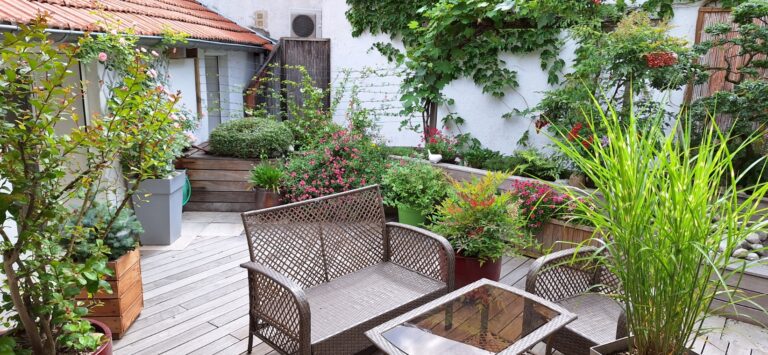 Cour-terrasse en bois remise en état, avec bacs fleuris, graminées et salon de jardin, à Andrézieux-Bouthéon