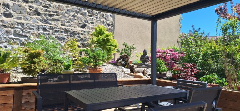 Terrasse sous pergola ouverte sur un jardin d'inspiration japonaise, avec érables du Japon, galets et bouddha, à Fontanès