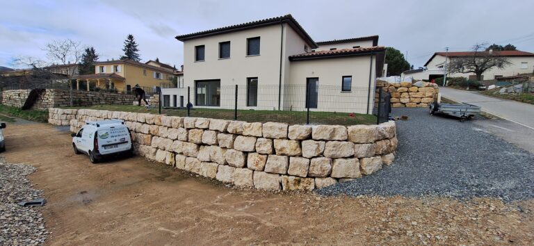 Clôture rigide et mur de soutènement en pierre autour d'une maison neuve
