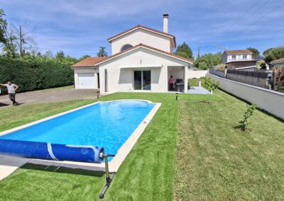 Gazon synthétique posé autour d'une piscine, avec vue sur la maison, à Sury-le-Comtal