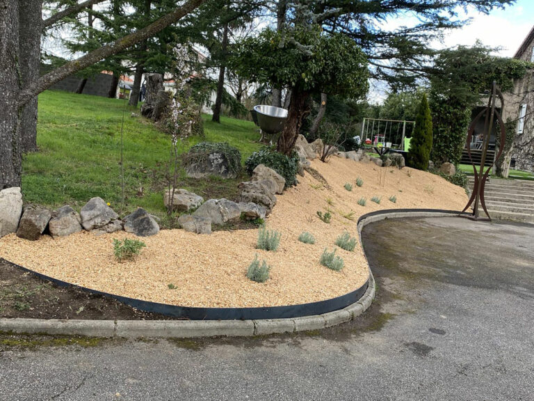 Massif paillé avec bordure métallique et rochers au pied des cèdres, en entrée de propriété à Sorbiers